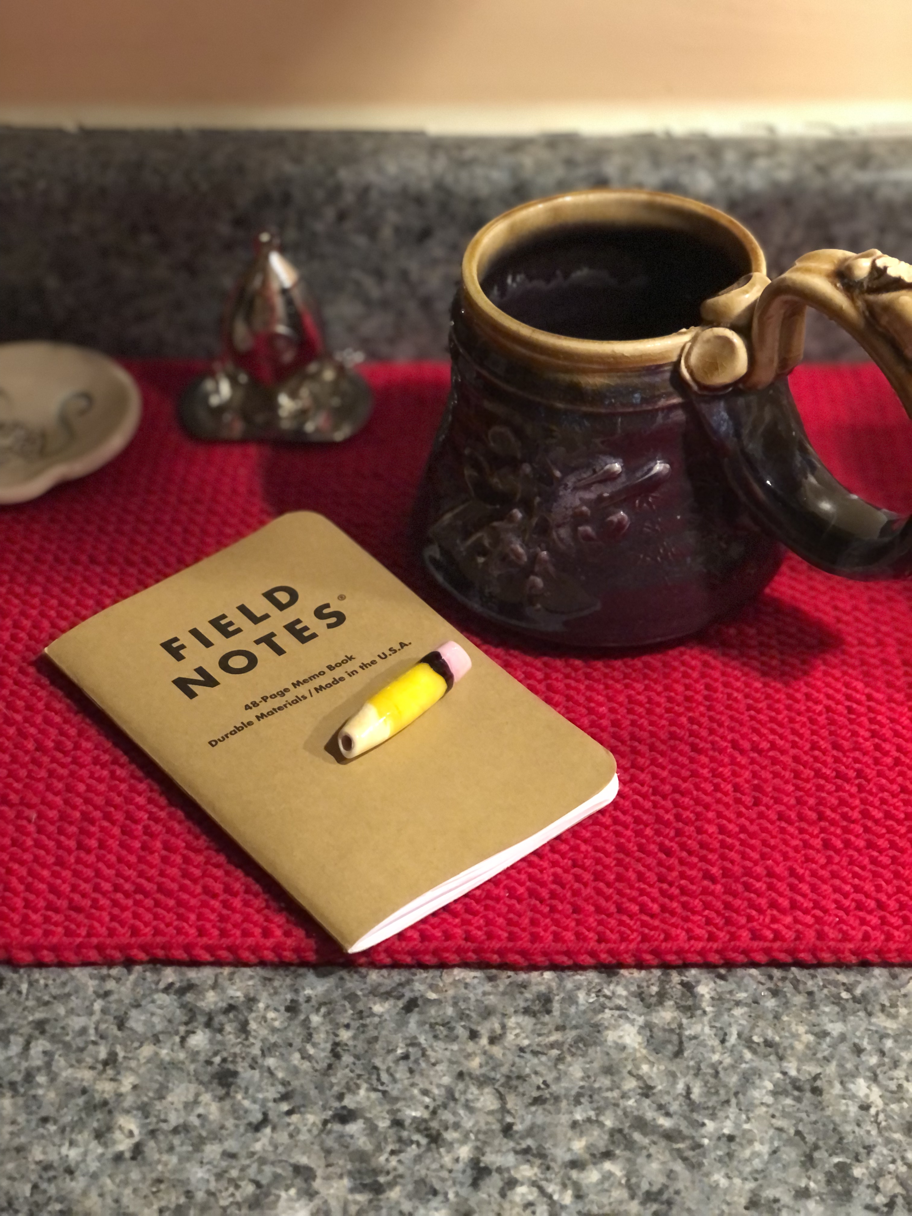 A mug next to a Field Notes notebook